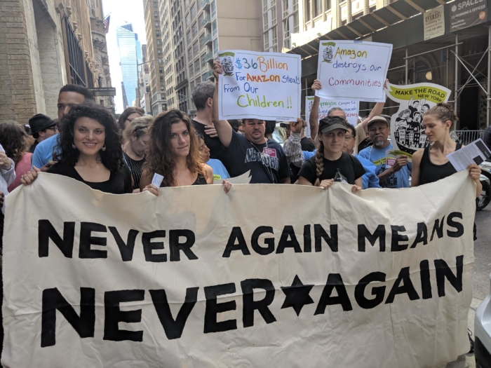 Image of protesters with banner reading "Never Again means never again."